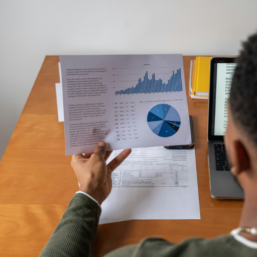 Reading a piece of paper over a mans shoulder that features text, graphs and pie charts