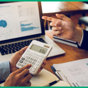 Close up of a calculator being held over the two discussions of reports